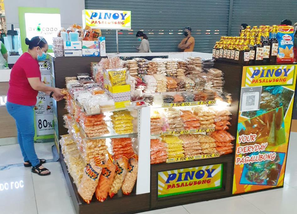 A woman arranges local snack items in her "Pinoy Pasalubong" stall at the center island of a mall. Photo courtesy of Philippine News Agency.