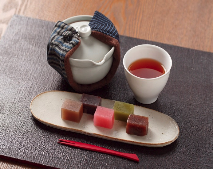 xicara de ch&aacute; preto da marca japonesa KUREHA e doces japoneses