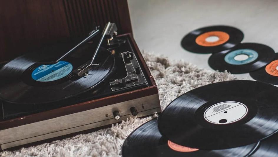 tocadiscos con vinilo rodeado de varios discos de vinilo