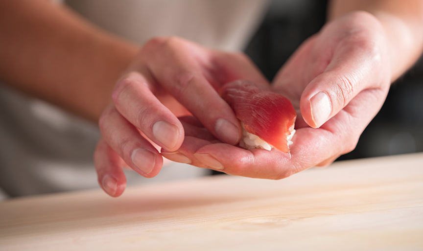 pessoa moldando o nigiri zushi na m&atilde;o
